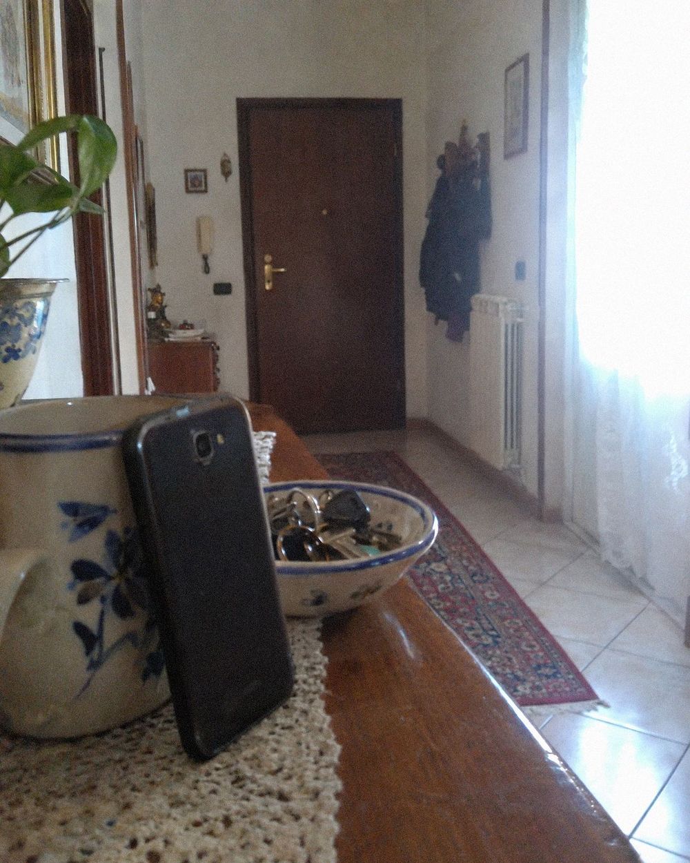 Un telefono appoggiato a una tazza su una mensola, puntato verso la porta di casa